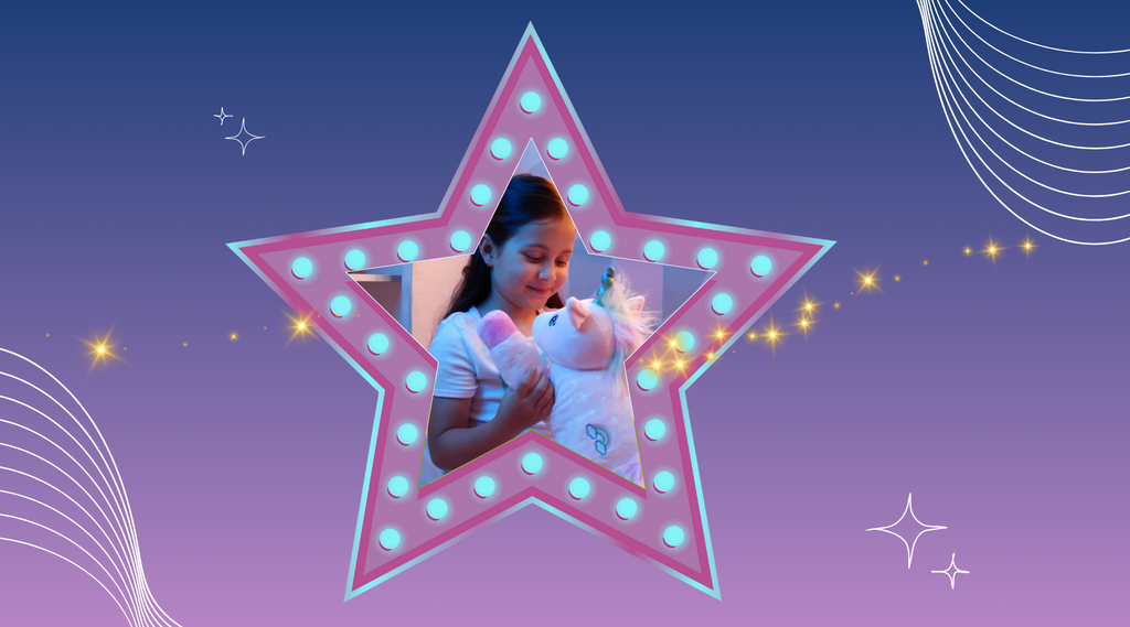 A girl in a star hugging Glimmer the Glowing Unicorn