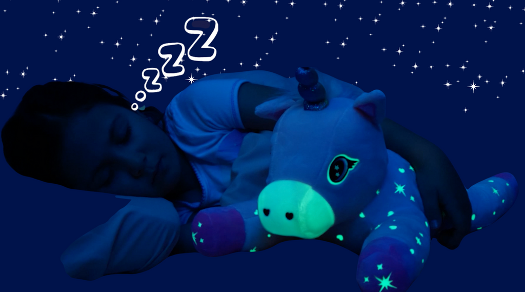 A girl sleeping at night hugging Glimmer the unicorn as she glows in the dark